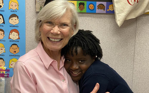 An older woman with gray hair and glasses smiles while a young girl hugs her—showing the joy of being a Mentor at First Presbyterian Church.