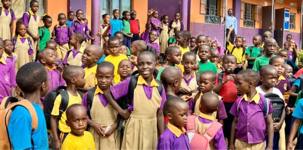 A large group of school children in colorful uniforms stand outside First Presbyterian Baton Rouge’s vibrant school building.