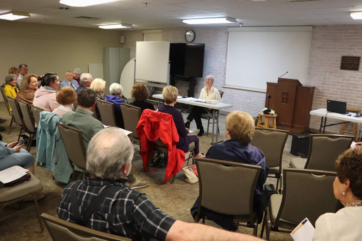 A group of adults listens as a woman speaks at a table during a First Presbyterian Baton Rouge church service.