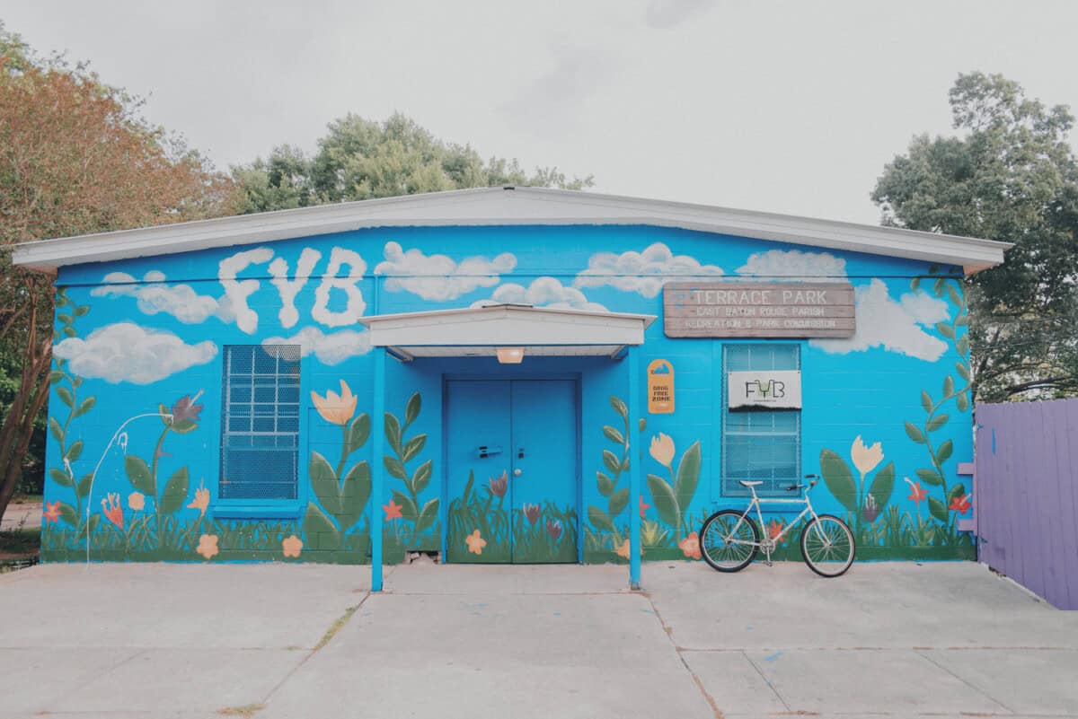 A blue building with a flower mural, a bike out front, and a 