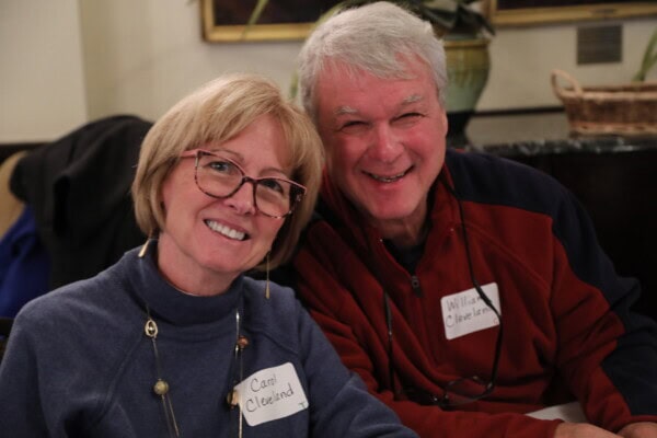 Two older adults with name tags smile indoors, attending a gathering at First Presbyterian Baton Rouge.