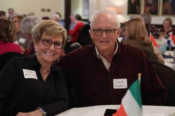 An older woman and man sit together at a crowded table during First Presbyterian Baton Rouge services, both smiling with name tags.