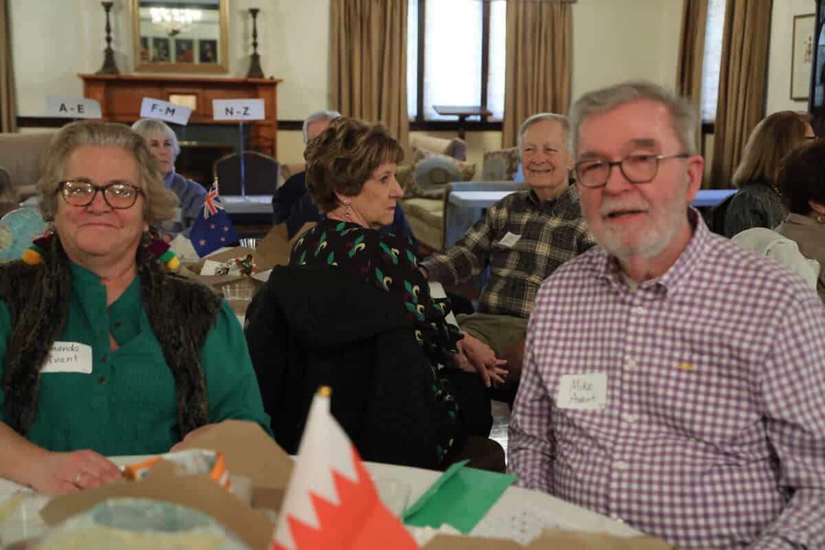 A group of older adults with name tags enjoy food and conversation at a First Presbyterian Baton Rouge indoor social event.