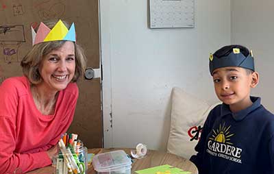 An adult and child in paper crowns smile at a table of crafts at First Presbyterian Baton Rouge.