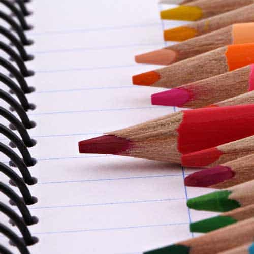 Close-up of colored pencils on a lined spiral notebook at First Presbyterian Baton Rouge, with tips pointing left.