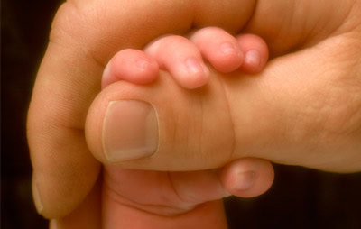 An adult hand gently holding a newborn’s, symbolizing care and connection at First Presbyterian Baton Rouge.