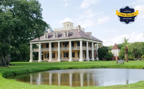 A large, historic plantation-style house—Houmas House—with columns stands by a pond, framed by trees and green grass. Logo in top right.