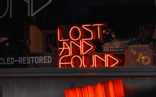 A red neon sign in a window reads "LOST AND FOUND," with some vintage items visible in the background.
